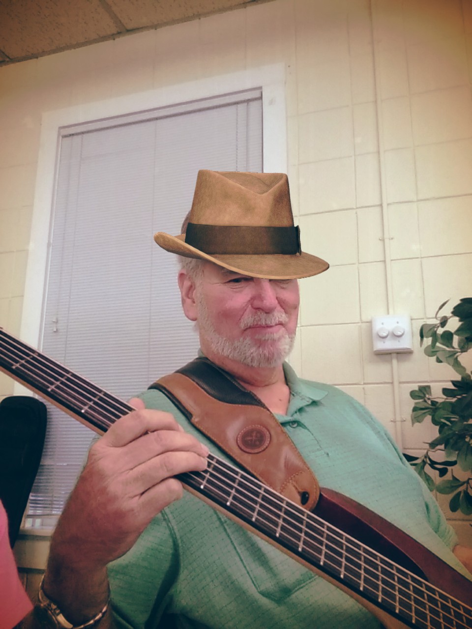 John Colby playing bass at an open mic while wearing a hat
